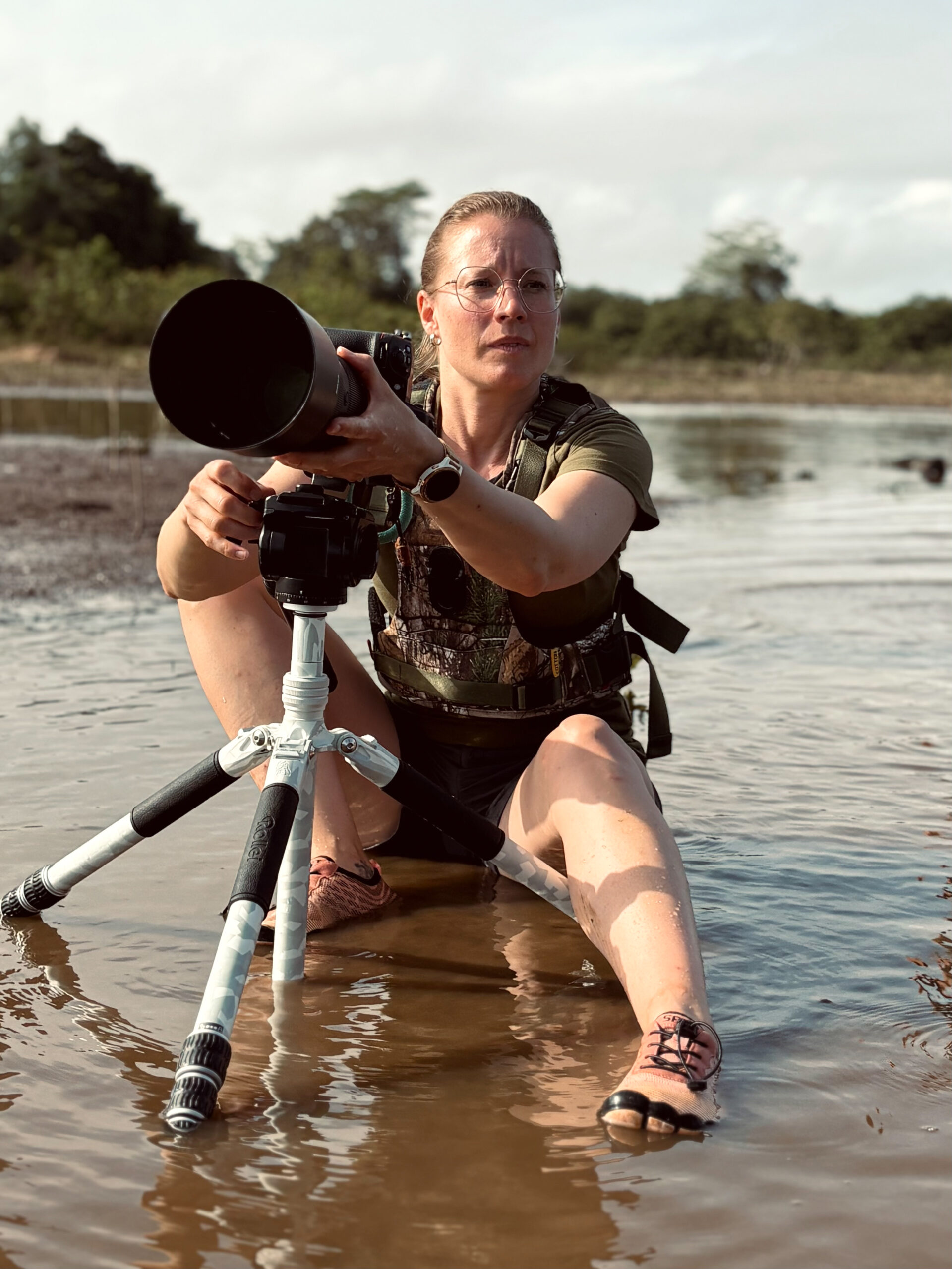 Fotografin arbeitet im flachen Wasser mit Stativ und Teleobjektiv